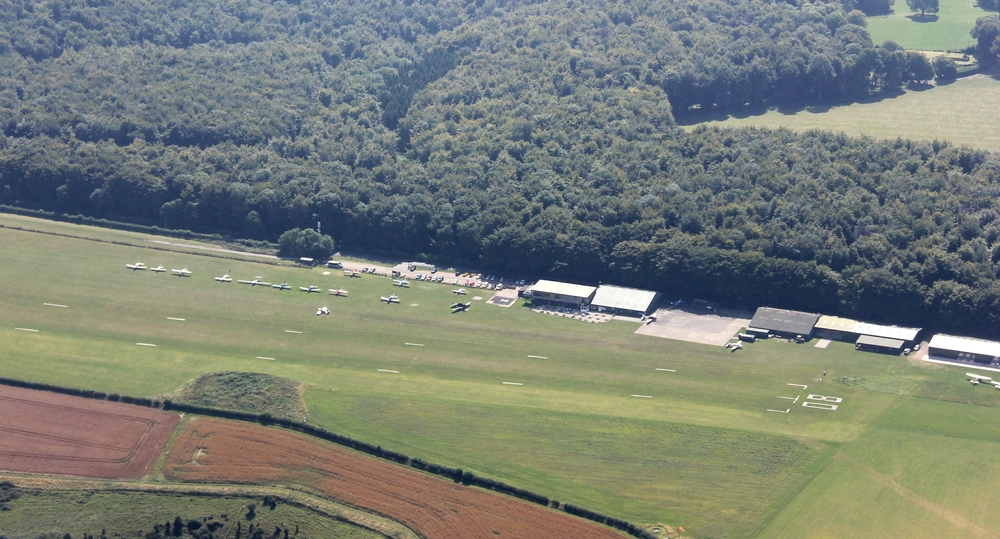 Compton Abbas airfield. You can see the runway marked out on the grass, a row of parked aircraft, and just make out the restaurant's outside seating area.