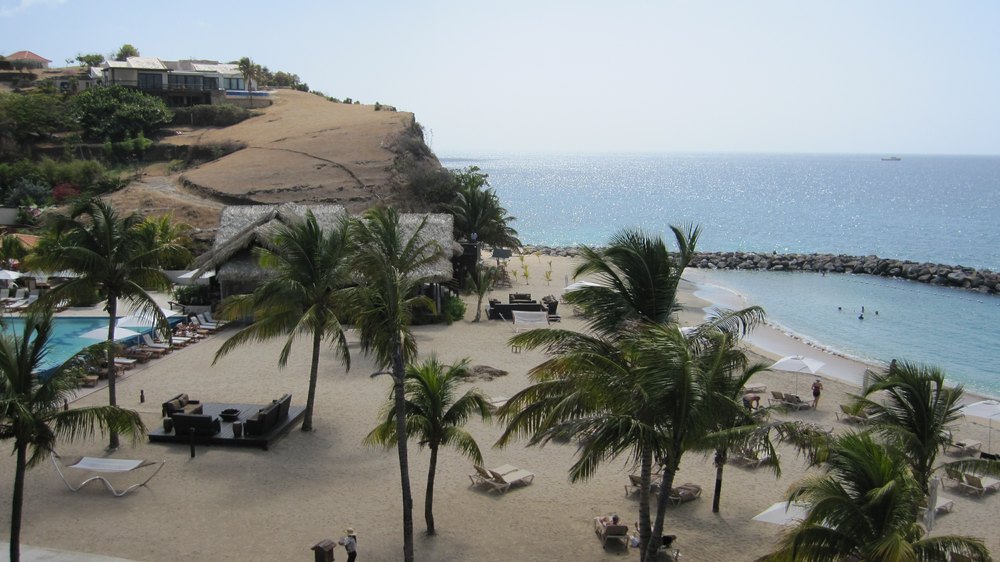View from the top of the Pink Gin buildings, looking west along 
				the beach. Neptunes is the thatched building between the beach and the Main Pool. The buildings at the top left are not part of Sandals 
				La Source - the previous owner of the hotel lives there with his family. 