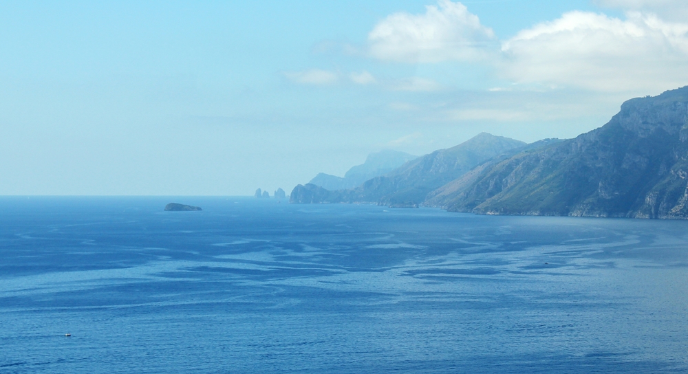 Way off in the distance, the island of Capri sticks its head above the mainland, and Capri's Faraglioni stacks are visible on the horizon next to the island.