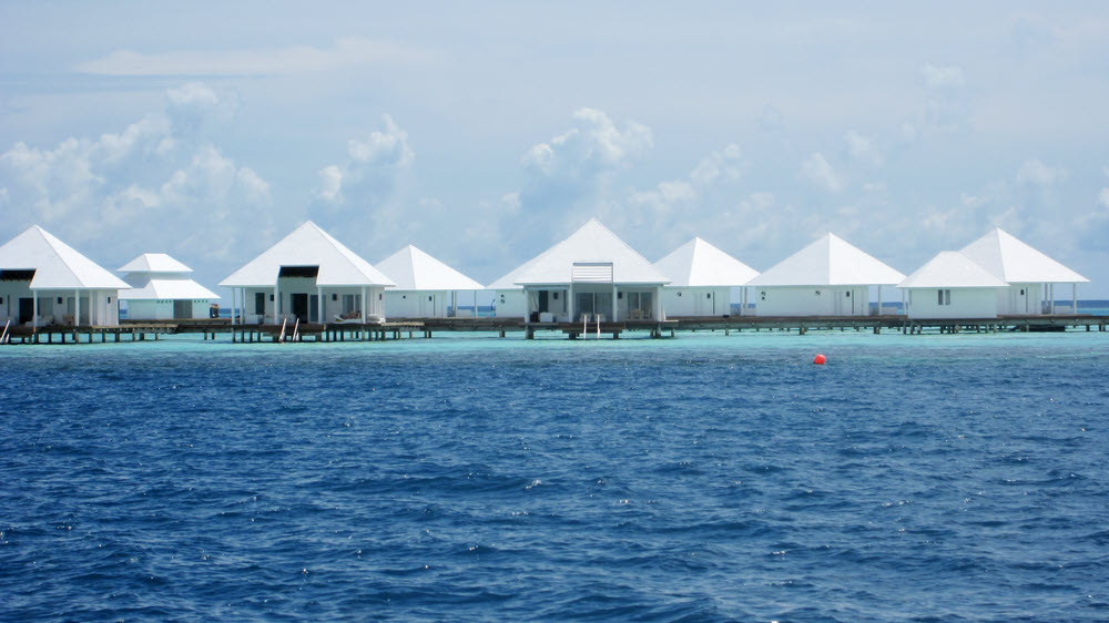 Water villas from the north. The red buoy marks the end of a passage cut through the coral reef to enable snorkellers to swim out to the drop-off.  (109k)