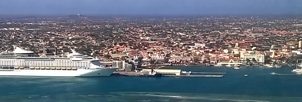 From the airplane, a massive cruise liner towers over the buildings of the capital, Oranjestad.