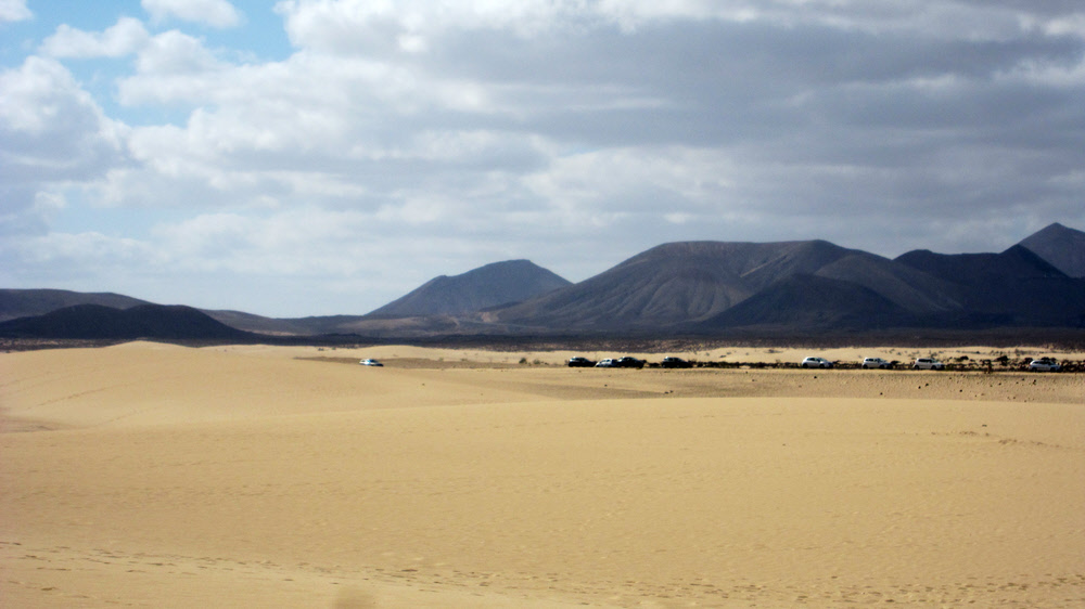 Cars parked on the main road which runs the length of the dunes a km or so back from the sea. (117k)