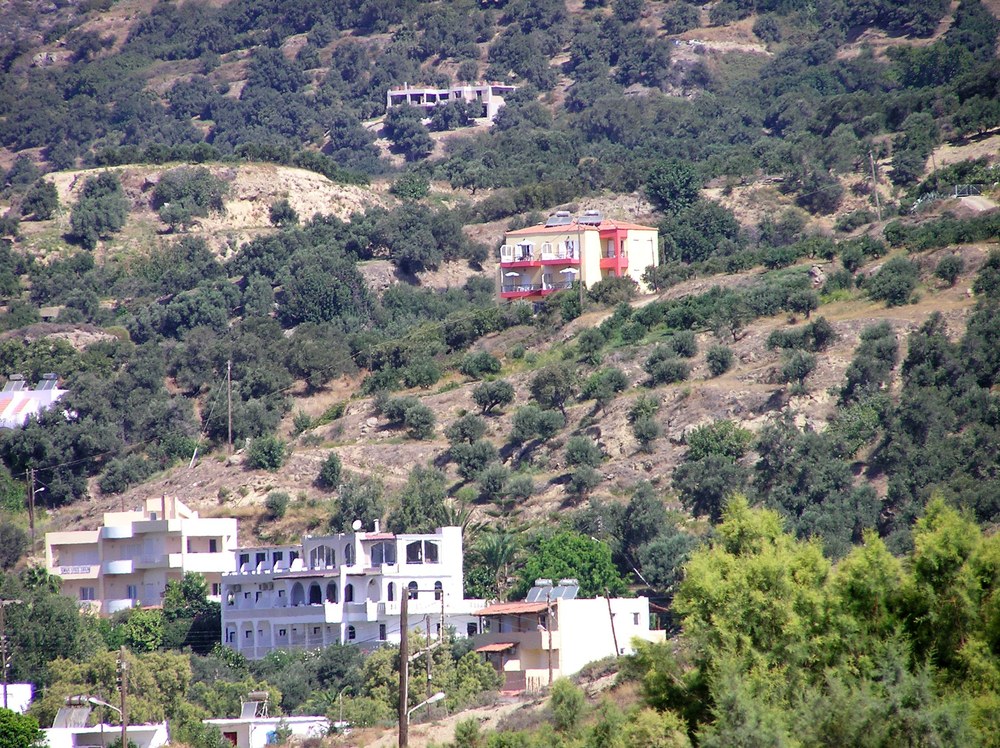 The cream and pink Atlas Apartments standing in splendid isolation high above Plakias.