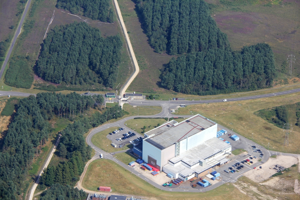 The security gate at Winfrith AEA. The public highway is visible at the top left, and the road running left to right across the photo is 
					Monterey Way. The security gate on Monterey Way is just above and to the left of the centre of the photo. This was the site of the dummy 
					airfield's Nissen hut and bomb shelter/control bunker.