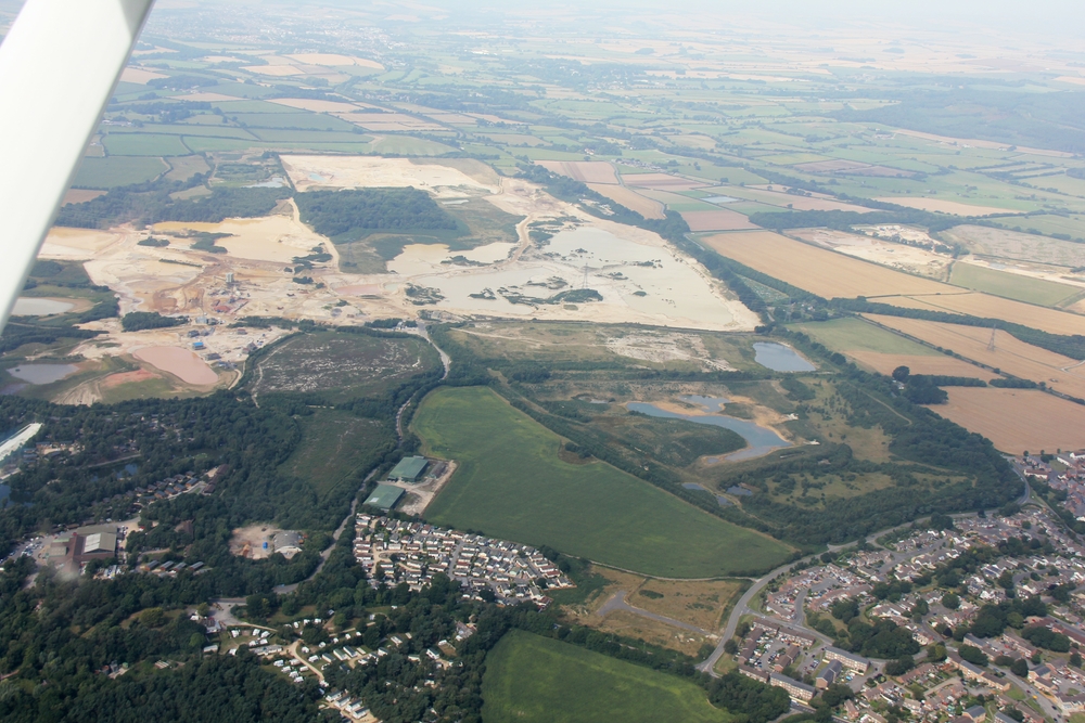 The village of Crossways, Dorset is at the bottom right. RAF Warmwell used to be on the area above and to the left of the village. 
					Millions of tons of gravel have been extracted from the site. The two large green buildings just below and to the left of centre are all 
					that remains of RAF Warmwell - two aircraft hangars, now used as storage barns by a local farmer.