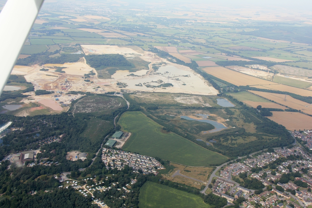 The village of Crossways, Dorset is at the bottom right. RAF Warmwell used to be on the area above and to the left of the village. 
					Millions of tons of gravel have been extracted from the site. The two large green buildings just below and to the left of centre are all 
					that remains of RAF Warmwell - two aircraft hangars, now used as storage barns by a local farmer.