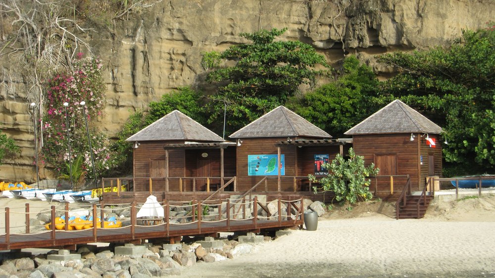 The Watersports Centre from the same pier. It's after 5pm, so it's closed. The right-hand end is reception and a shop, the centre section is 
					a hanging room for BCDs, wetsuits etc, and the left-hand end is staff quarters and workshop. Beyond that are rinse tanks, showers and WCs.