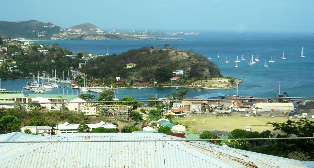 On a tour round the island. Here's a view to the west across St George's harbour, with Grande Anse bay beach at the upper left. In the 
						far distance is Sandals La Source at the western end of the island. 
