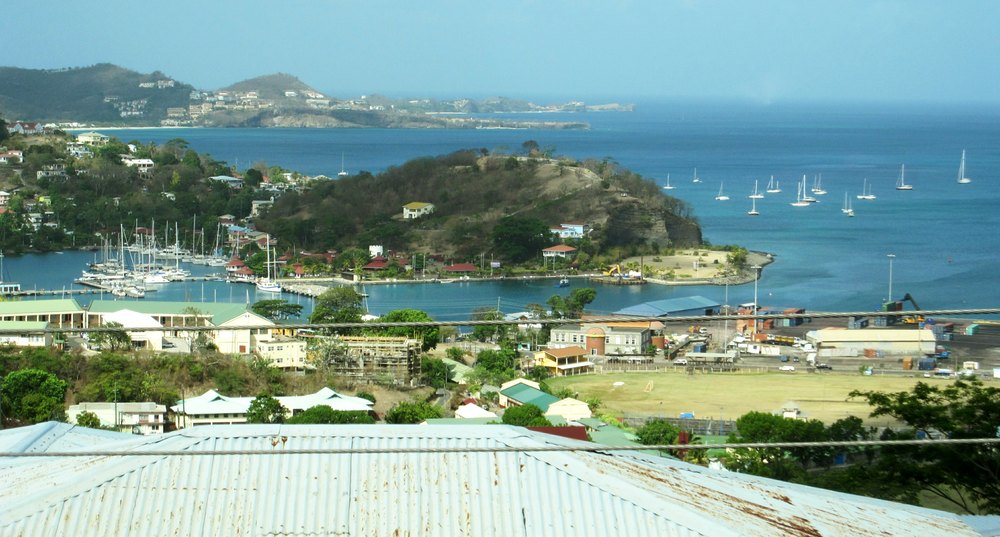 On a tour round the island. Here's a view to the west across St George's harbour, with Grande Anse bay beach at the upper left. In the 
						far distance is Sandals La Source at the western end of the island. 