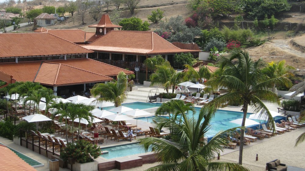 The Main Pool, with The Living Room behind it to the left: a 
				combined bar, seating and entertainment area. The balcony of Spice's restaurant is at the back, below the clock tower.