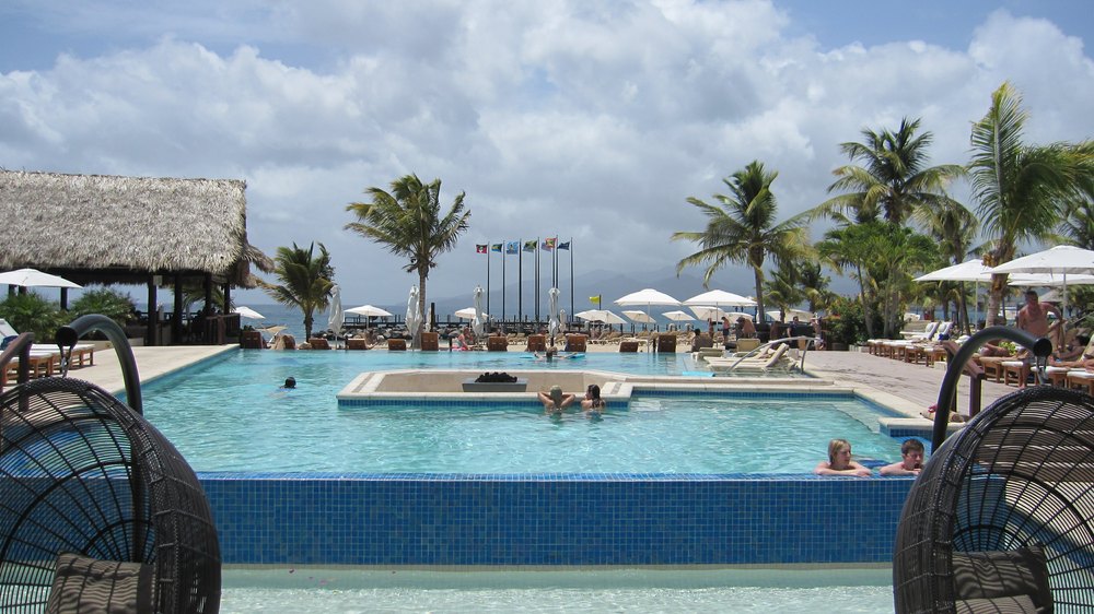 The view from The Living Room over the Main Pool to the beach, with the mountains above St George's in the far distance across the bay.