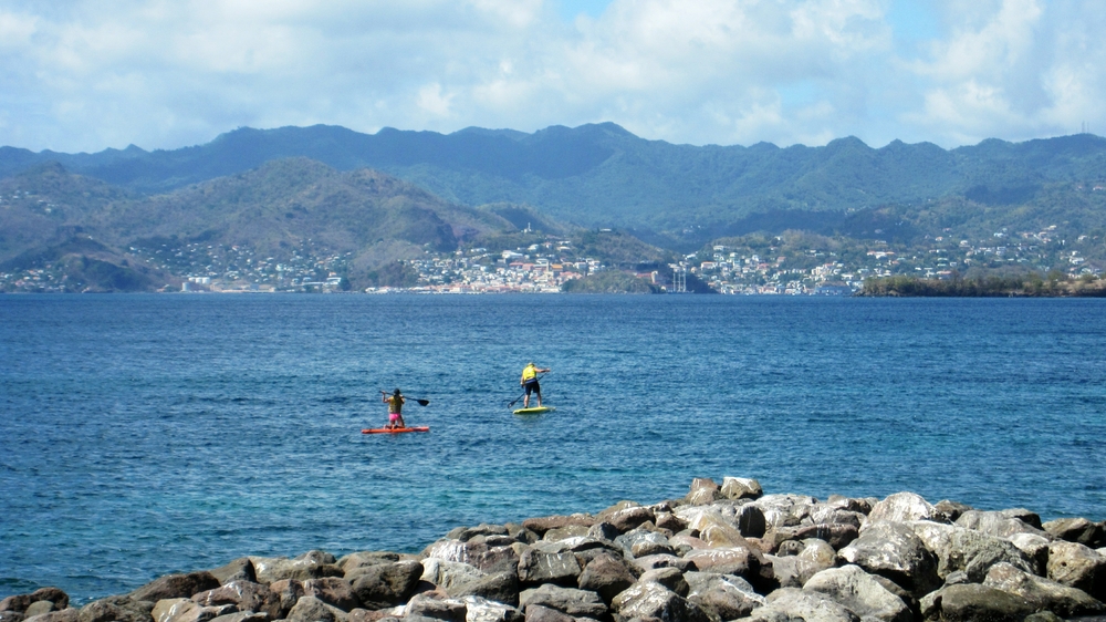 Outside the breakwater by the watersports centre, a couple try to paddle across Grande Anse bay to the capital, St George's.