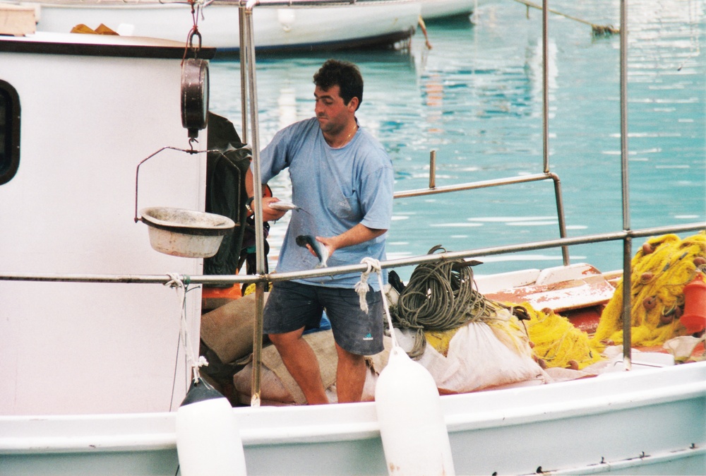 A fisherman at Fiskardo, Kephalonia weighs his catch.