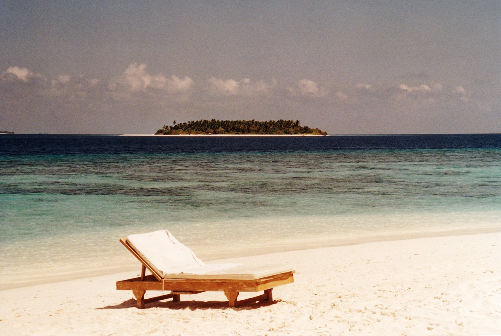 On the beach outside our room - the Robinson Crusoe island in the distance. 
          The house reef out to the drop-off is clearly visible.