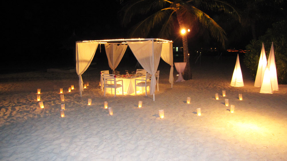 A table prepared for dining under the stars after a wedding on the beach ...