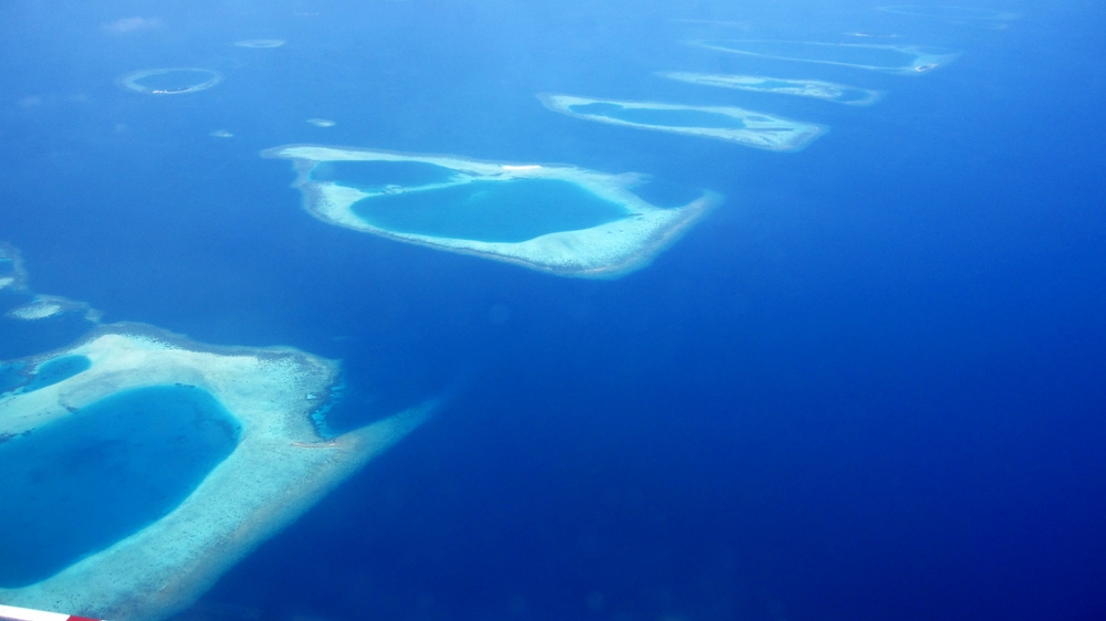 The eastern edge of Ari Atoll, as seen from the seaplane at about 2000 feet. Deep water on the right, shallower on the left. Some of the 
					numerous reefs marking the edge of the atoll form a straight line. There's a small yellowy sandbank just sticking its head above water 
					just above the middle of the photo. Everything else is seen through a couple of metres of transparent ocean.