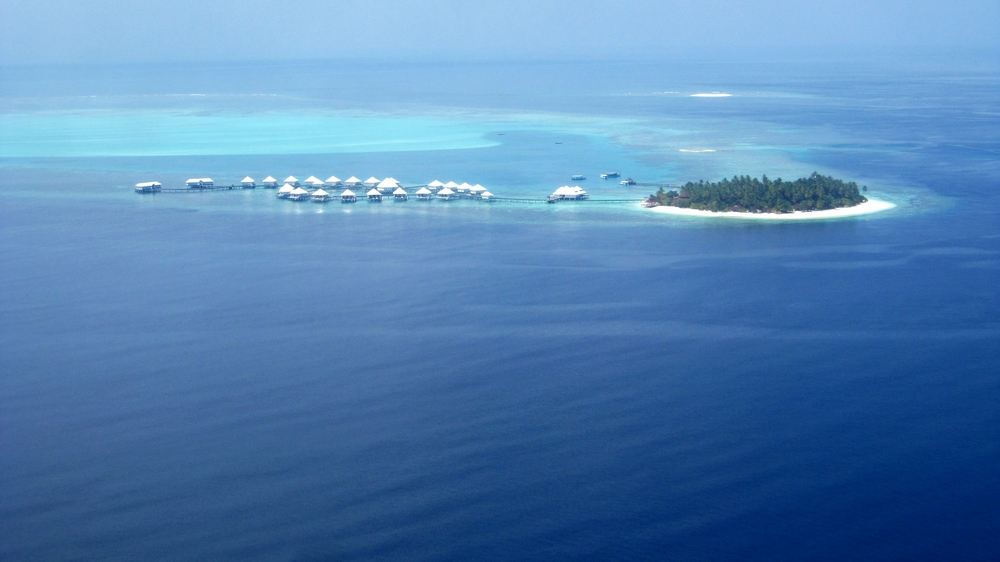 Thudufushi island from the seaplane as we do our downwind leg, with the water villas stretched out along the reef. We'll be 
						landing just behind them. The Panettone sandbank, marking Manta Point, is towards the upper right.