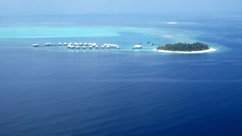 Thudufushi island from the seaplane as we do our downwind leg, with the water villas stretched out along the reef. We'll be 
						landing just behind them. The Panettone sandbank, marking Manta Point, is towards the upper right.