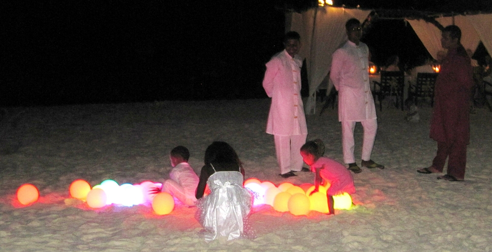 The lighted spheres fascinate a couple of toddlers, while some of the waiters watch.