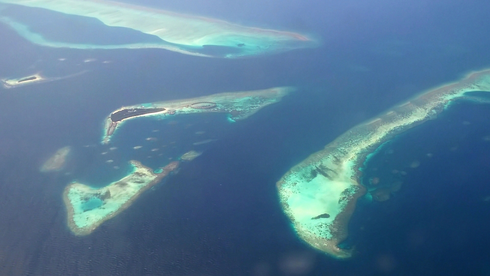 On our way to Meedhupparu on the seaplane. A resort island with lots of water villas in North Male Atoll. The reefs at the right and at the top are several metres 
					under water.