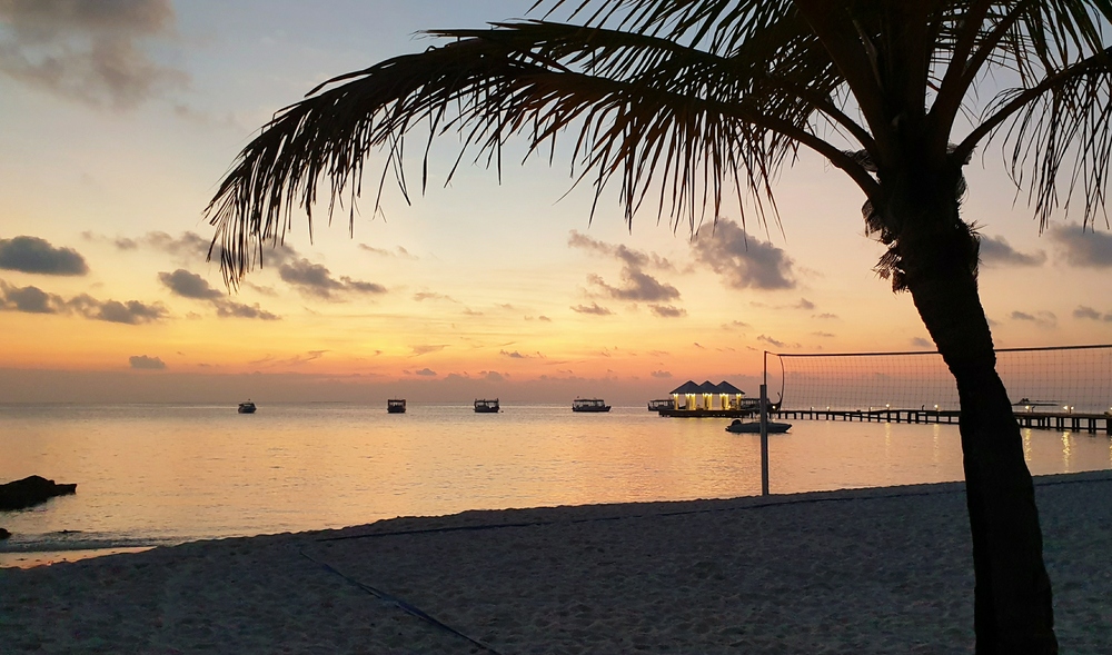 Sunset on the beach, with the main jetty on the right, and several dhonis moored in the lagoon overnight.