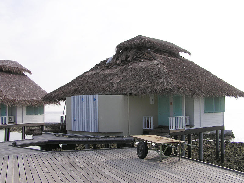 One of the semi-detached water bungalow buildings.�This one was being re-thatched. (115k)