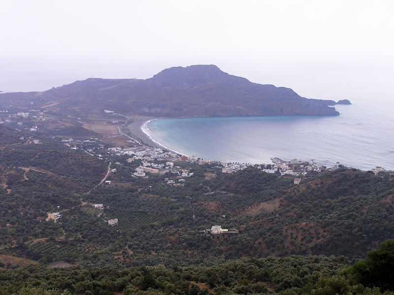 Plakias bay from up in the mountains.�The harbour jetty is visible at the right, with the beach sweeping around to the cape in the background.  (92k)