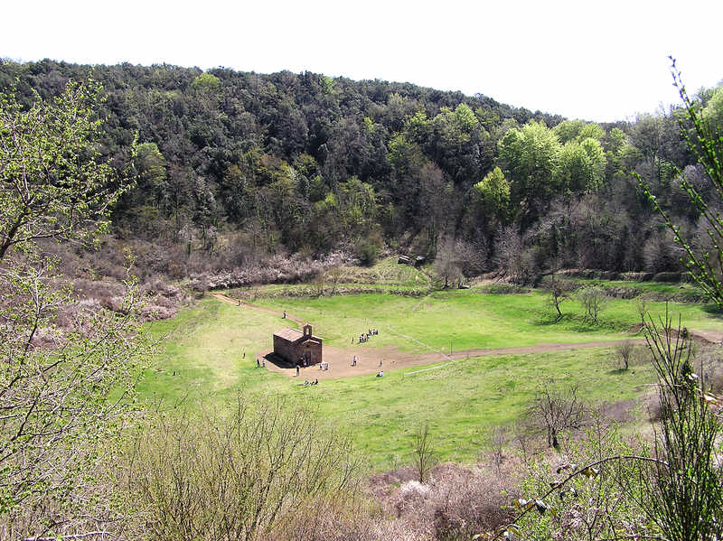 The church at the bottom of the crater of the Volca de Santa Margarida, with the tree-clad crater wall beyond.  (117k)