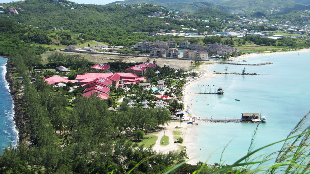 Sandals Grande St Lucian, with the red roofs, stretches from the pier in the foreground to the breakwater with two small trees on in the middle distance. 
        Rodney Bay is to the right, and the Caribbean stretches off to the left towards Martinique. This view is from Signal Peak on Pigeon Island. (163k)