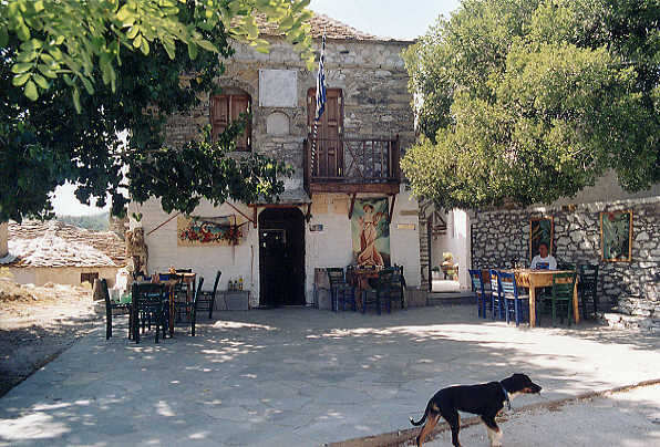 Linda enjoying a beer in the shade at the taverna in the main square at Kastro. The church is behind her. (61k)