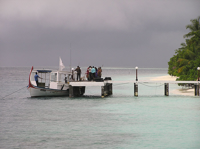 A threatening sky over Vilamendhoo as a troupe of cleaning ladies arrive by boat from a nearby island.  (67k)
